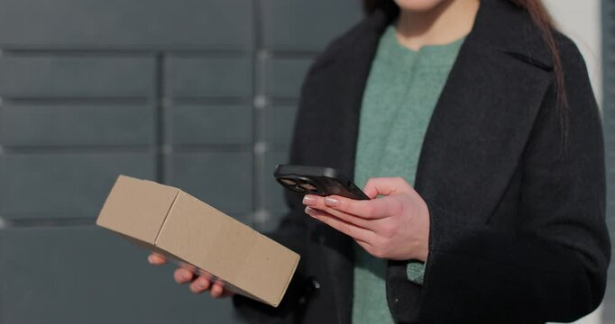 Close up woman collecting parcel from shopping locker. Mail delivery and post service, online shopping, e commerce concept.