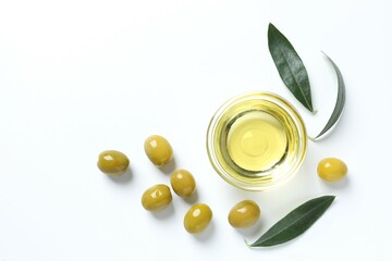 Bowl of fresh olive oil and olives with leaves on white background
