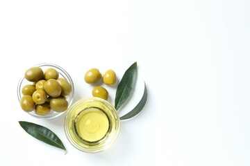 Bowl of fresh olive oil and olives with leaves on white background