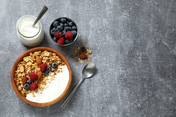 Delicious granola with berries and yogurt on a gray background