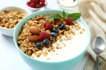Delicious granola with berries and yogurt on a light background