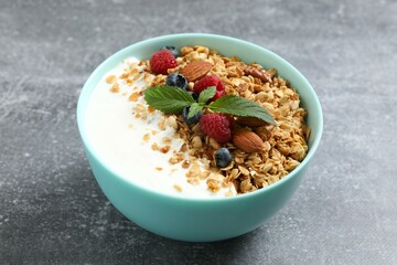 Delicious granola with berries and yogurt on a gray background