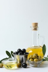 Bottle of fresh olive oil and olives with leaves on the table