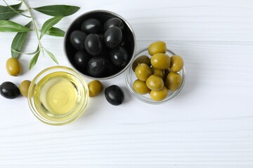 Bowl of fresh olive oil and olives with leaves on the table