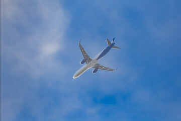 Passenger plane against blue sky, view from below.
