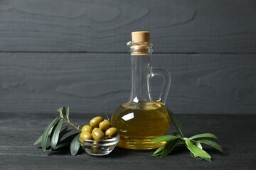 Bottle of fresh olive oil and olives with leaves on the table