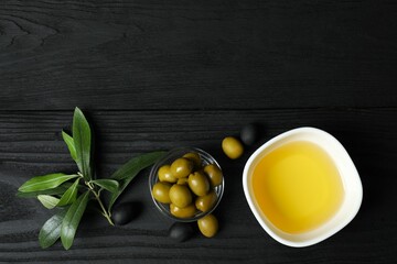 Bowl of fresh olive oil and olives with leaves on the table