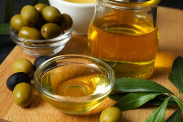 Bowl of fresh olive oil and olives with leaves on the table