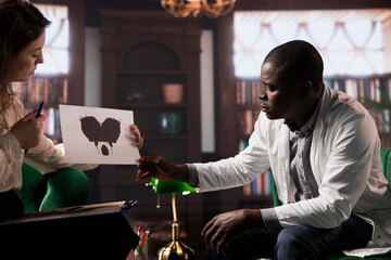 Specialist presents a Rorschach test to a doctor in white coat, looking for answers with...