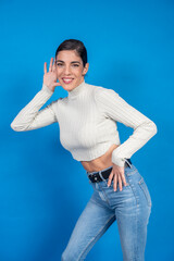 Curious young woman listening carefully, holding hand to ear on blue background