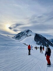 Ski slope with sun and clouds and skiers and snowboarders