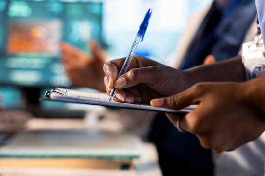 Medical assistant takes notes on hospital records files during checkup and discussion with old people. Female nurse helps medic collecting information and symptoms for recovery plan. Close up.