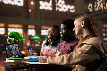 Diverse group of pupils attending online class webinar from the campus library, participate at remote courses while they can work on their bachelor degree. Academic research within the institute.