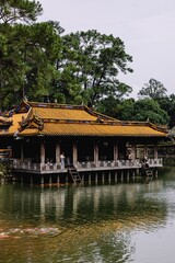 Fototapeta premium Traditional architecture with yellow-tiled roof and pond reflection.