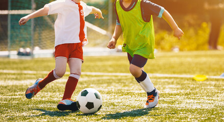 Two School Boys Kicking Football Ball in a Game. Duel of Soccer Kids. Children Playing Soccer Match on Grass Football Pitch in a Sunny Day
