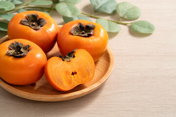 Fresh ripe persimmon fruit on wooden table background.