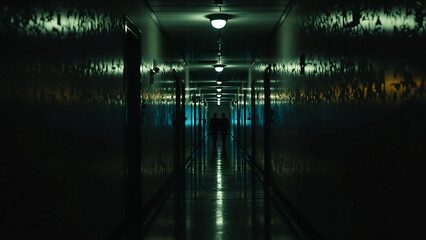 Two Silhouetted Figures Walking in the Dark Long Corridor with Dim Lights Overhead