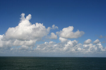 Seascape with white clouds in a blue sky and the North Sea on the coast of The Netherlands