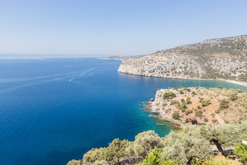 Stunning view of a rugged coastline with vibrant blue sea and rocky cliffs under clear skies.
