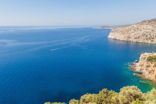 Stunning view of a rugged coastline with vibrant blue sea and rocky cliffs under clear skies.