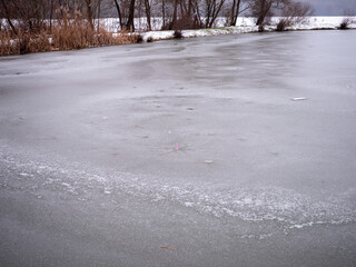 A frozen glass bottle in the pond.Thin ice surrounds the neck of an empty glass bottle.