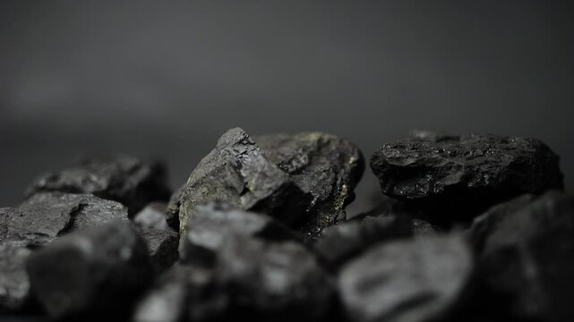 Pieces of coal fall in slow motion, colliding and shattering into fragments. A macro view of fossil fuel, ideal for presentations on energy resources.