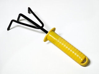 A yellow-handled gardening tool with black metal prongs, designed for digging, cultivating, or loosening soil.