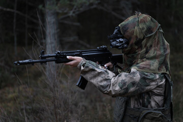 A young girl special forces soldier in a gas mask, camouflage and a tactical helmet with a night...
