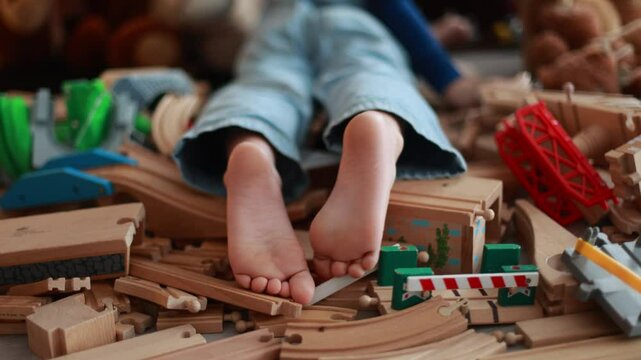 Child, cute boy, playing with toys in a playroom, focus on his feet