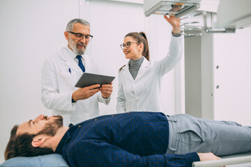 Obraz premium Mature doctor discussing with medical nurse in x-rays machine room. 