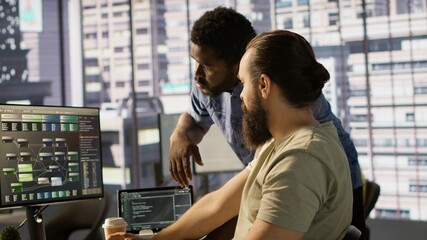 Manager correcting programmer mistakes while conducting code review to fix errors, identifying technical issues with company software. Team leader supervising IT staff member optimizing code, camera A