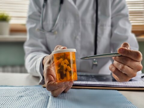 Female doctor hand holding pack of different tablet blisters at workplace closeup. Panacea, life save service, prescribe medicament