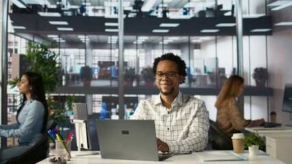Account executive multitasking on his computer to finish business tasks and operations. African...