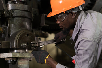 Male engineer repairing and maintenance heavy lathe machine in industry factory. Male technician worker checking parts of lathe machine at workshop