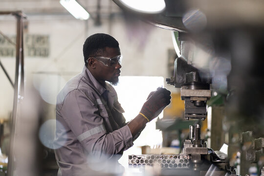 Male engineer repairing and maintenance heavy lathe machine in industry factory. Male technician worker checking parts of lathe machine at workshop
