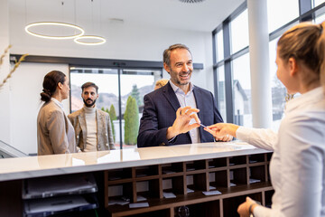 Businessman arriving in a hotel with his colleagues for a business conference, checking in at the reception.