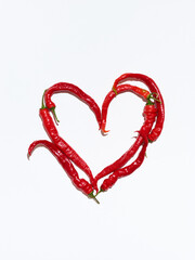 Green and red chili peppers in shape of a heart on white background