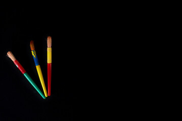 Three Colorful Paintbrushes Placed on a Black Background