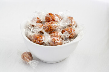 Petits œufs de nougatine en papillote, placés dans un bol blanc.