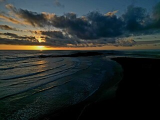 Aerial view of waves on a sandy beach at 90 Mile Beach, New Zealand, at sunset