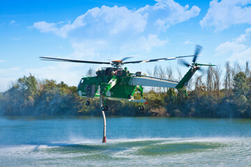 Italian CFS 103 fire fighting helicopter flying over a lake to collects water through a suction...