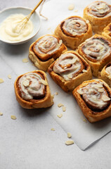 Freshly baked cinnamon rolls topped with cream cheese frosting and almond slivers