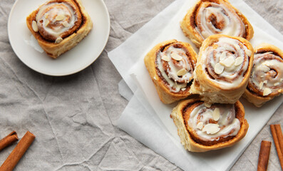 Delicious cinnamon rolls topped with icing and almonds on baking paper