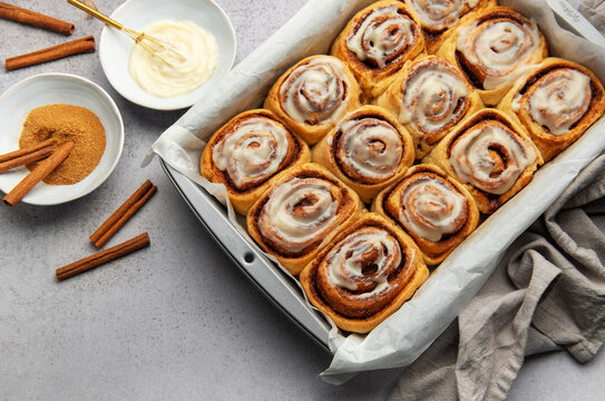 Freshly baked cinnamon rolls with cream cheese frosting in baking pan