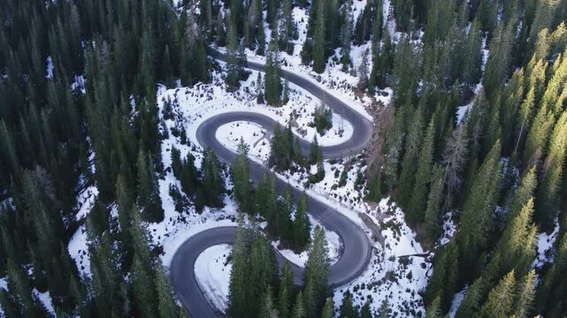 Aerial view of winding mountain road in the forest with snow, Dolomites, Italy