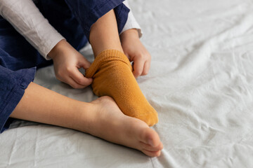 Child removing yellow socks on bed. Getting ready for bedtime