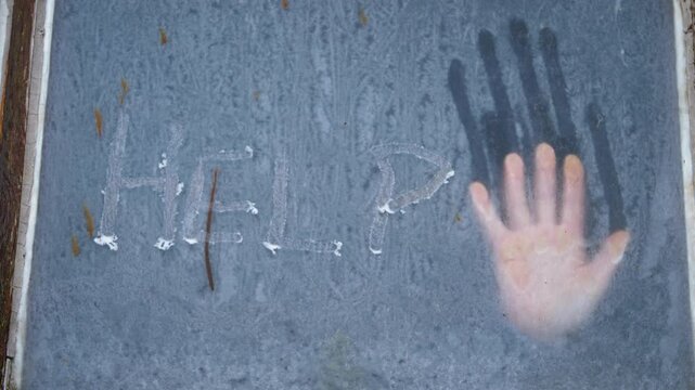 Help written in ice on winter window with human hand