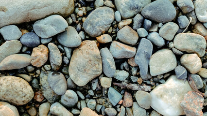 Stones of different sizes, colors and shapes lie on the ground.