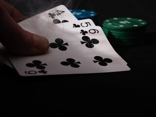 Poker player holding flush playying cards smoke atmosphere