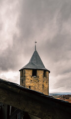 Fototapeta premium Medieval watchtower of Carcassonne under a cloudy sky seen from a wooden roof.